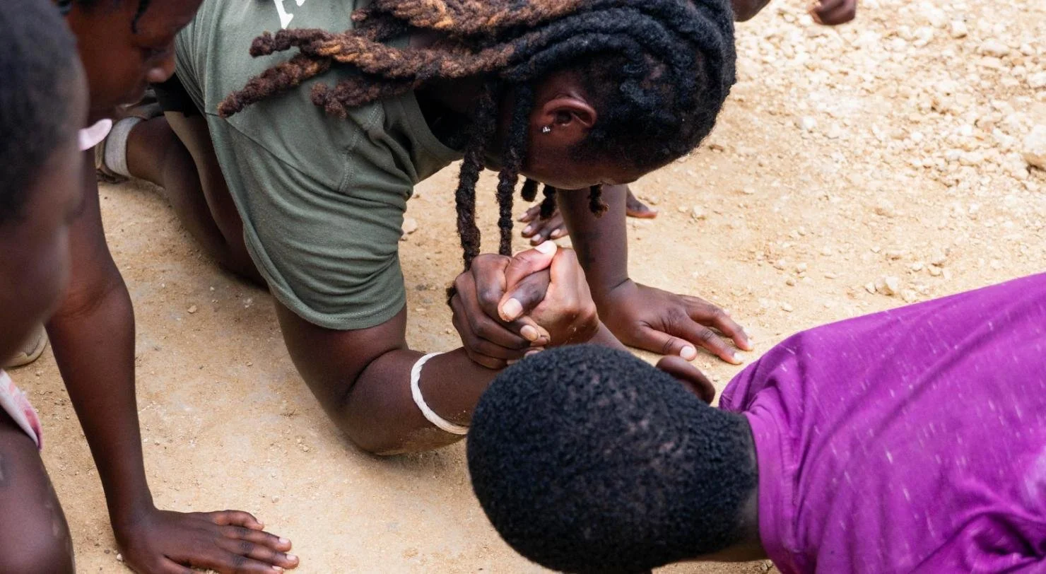 A student kneels to pray with a child