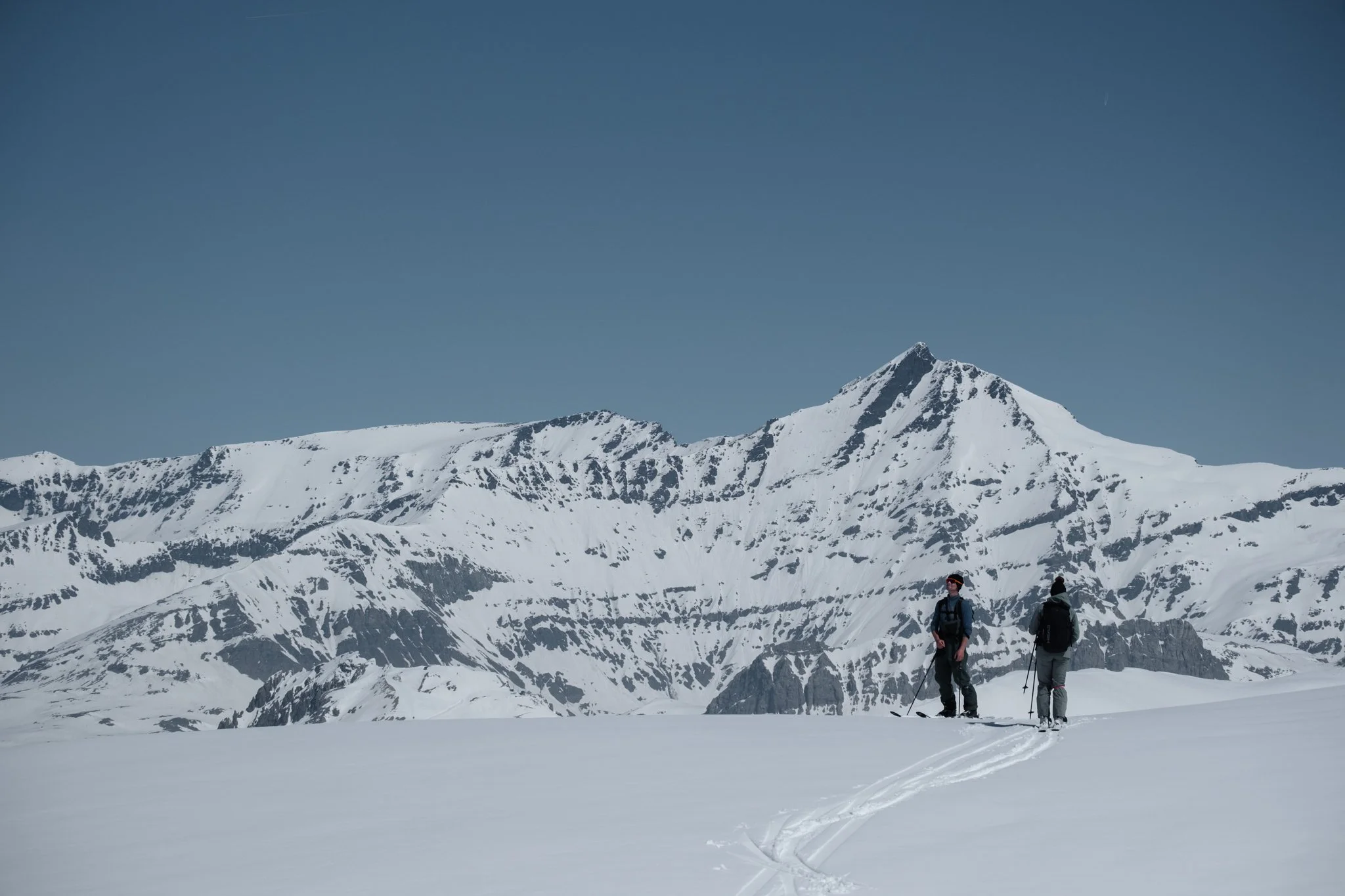 Two skiers beneath snow-covered mountain peaks