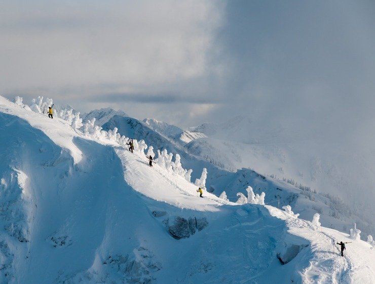 Skiers beside a snow-covered ridge at Revelstoke