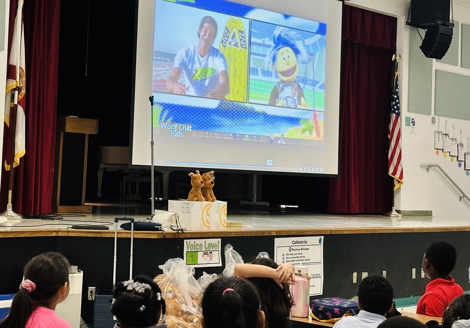 Students watching Messy live on screen with a surfing guest at a school assembly