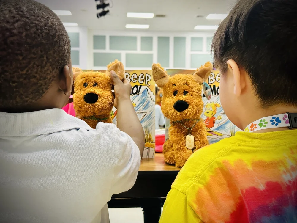 Two students with Gizmo plush toys and Beep, Beep, Gizmo! books