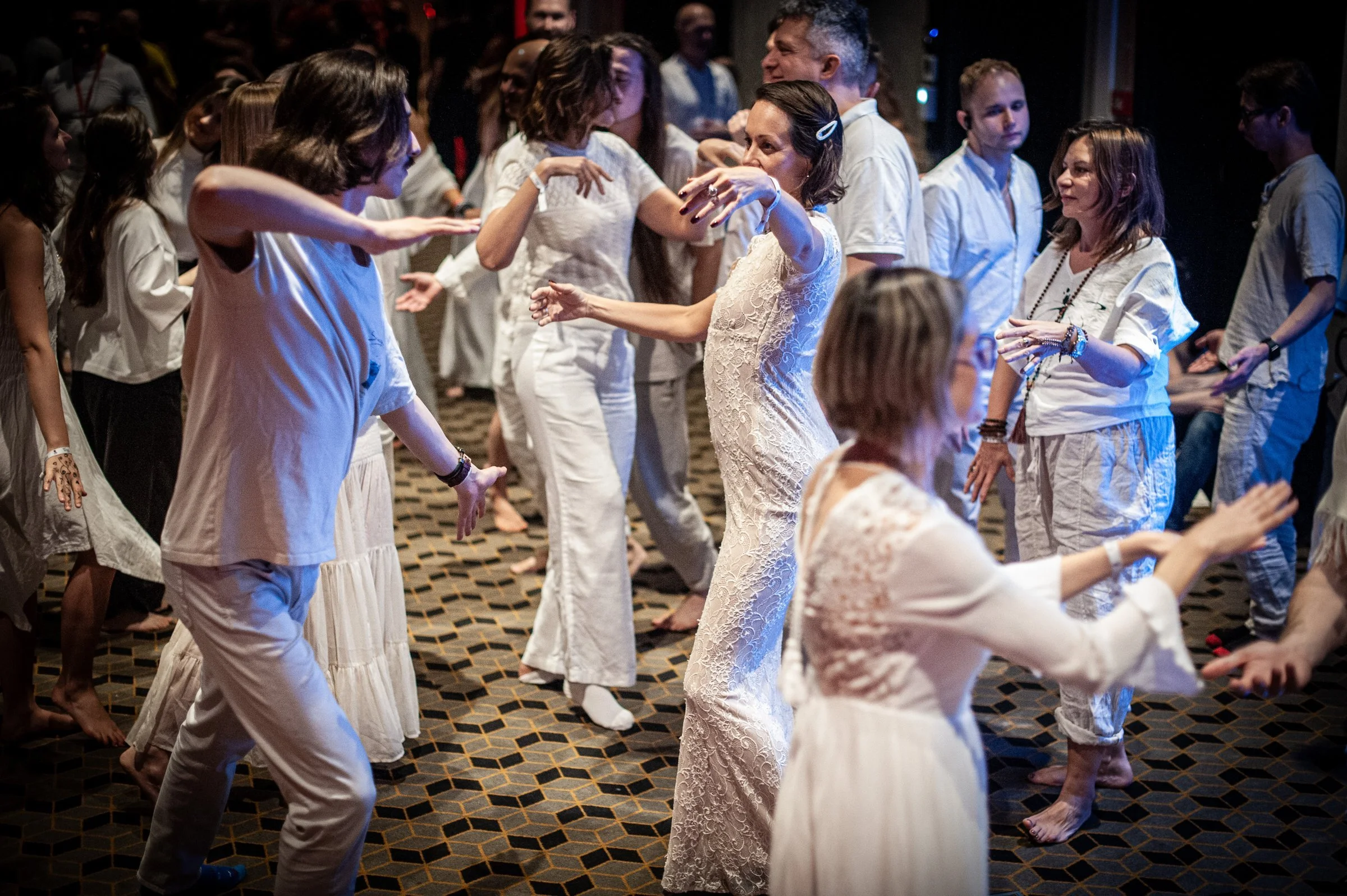 Participants in white gathered together in a warmly lit ceremony circle at Poland Tantra Festival