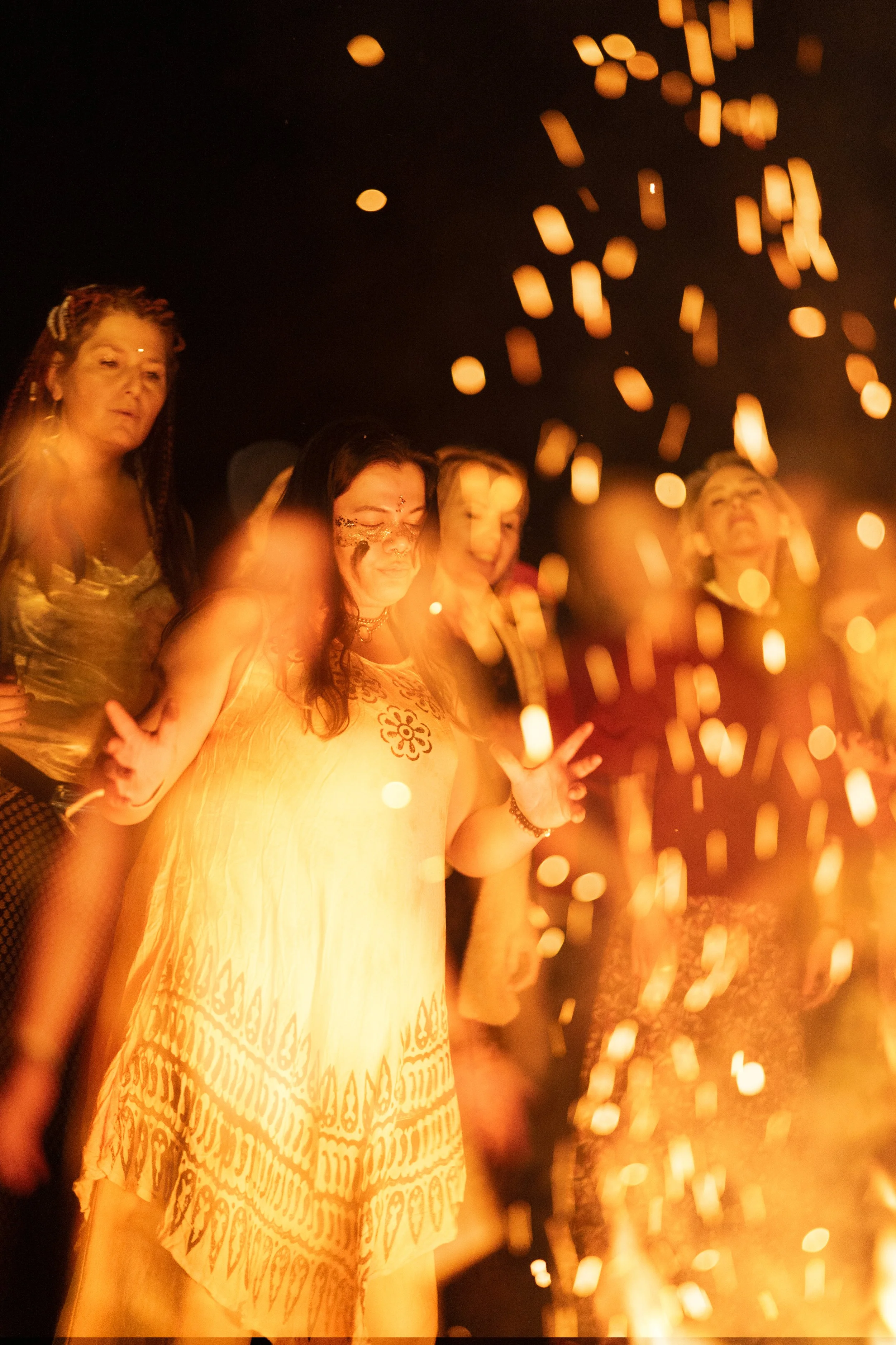 Festival participants dancing in warm firelight, arms raised, at Poland Tantra Festival