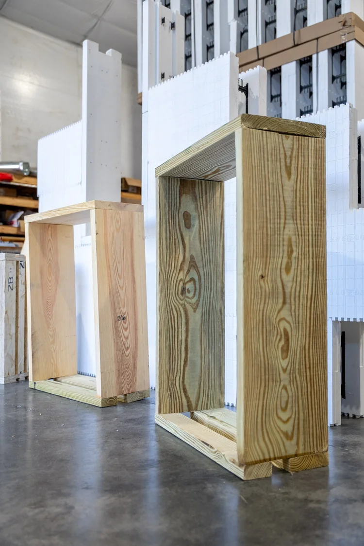 Two open-frame window bucks built from pressure-treated lumber standing on a warehouse floor