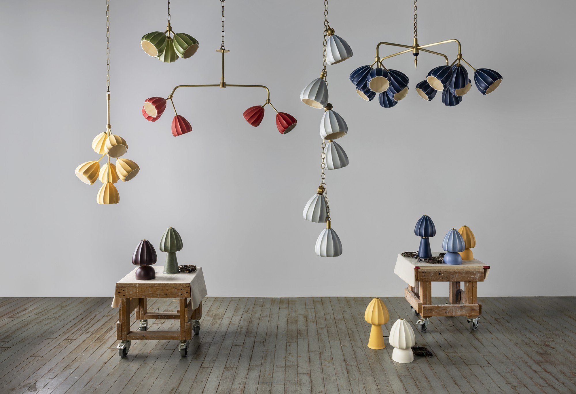 Hwang Bishop’s Bloom collection, with navy and pale-blue hanging fixtures and colorful ceramic table lamps displayed in the studio.
