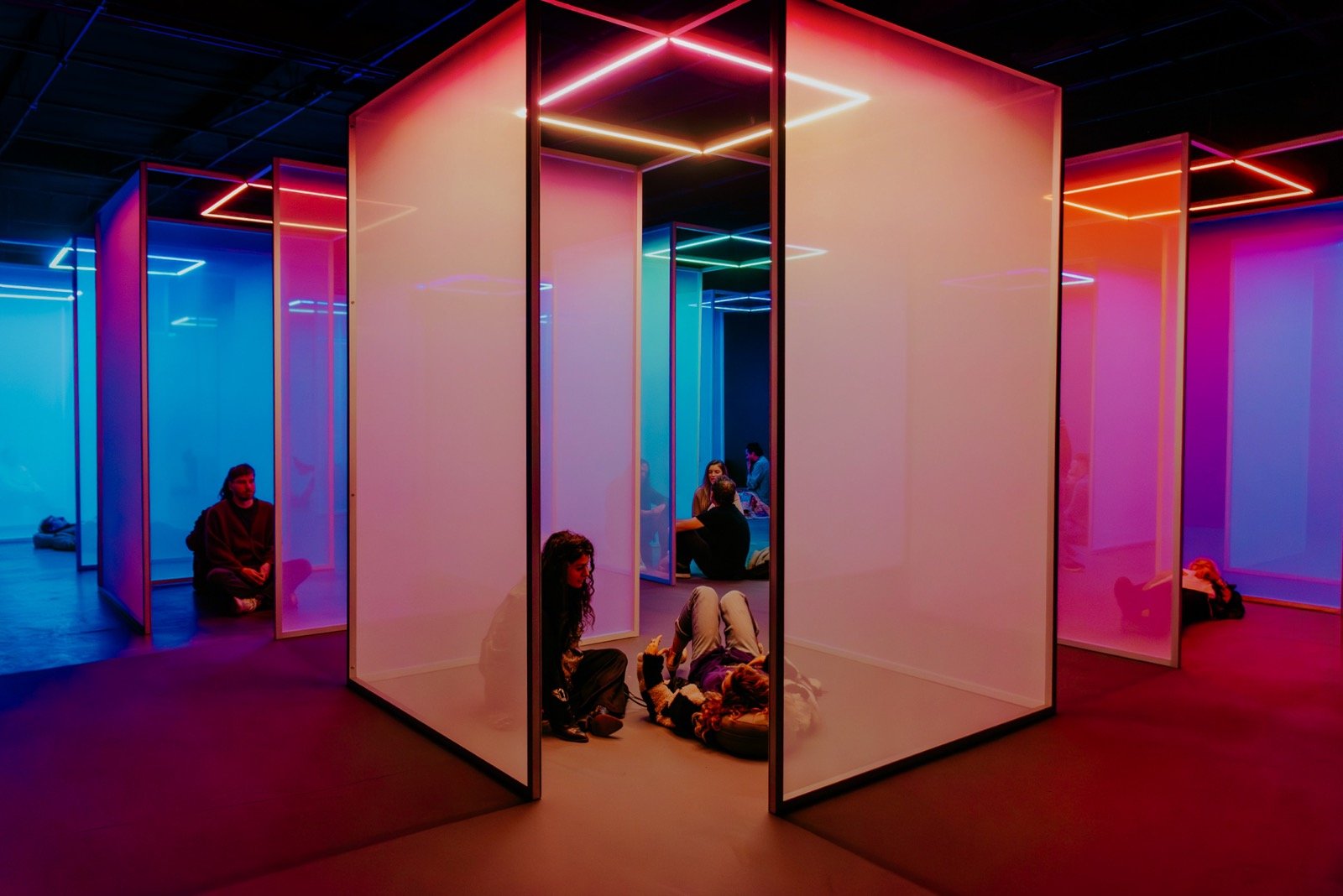 Visitors within glowing blue, orange and purple rooms at Chromasonic Field in Los Angeles.