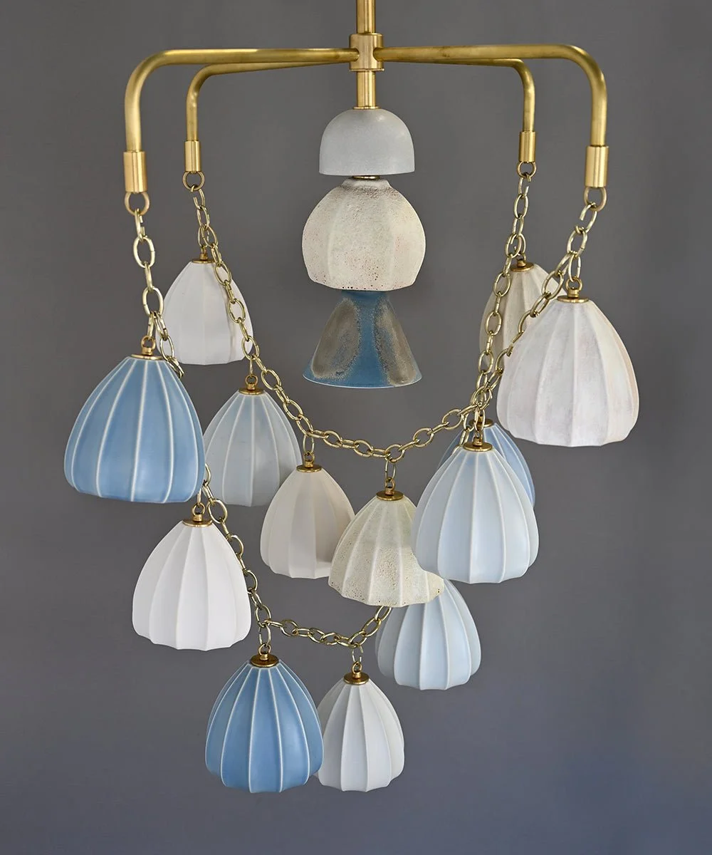 A sculptural Bloom chandelier with pale blue, cream and textured ceramic shades suspended from brass arms and chains.