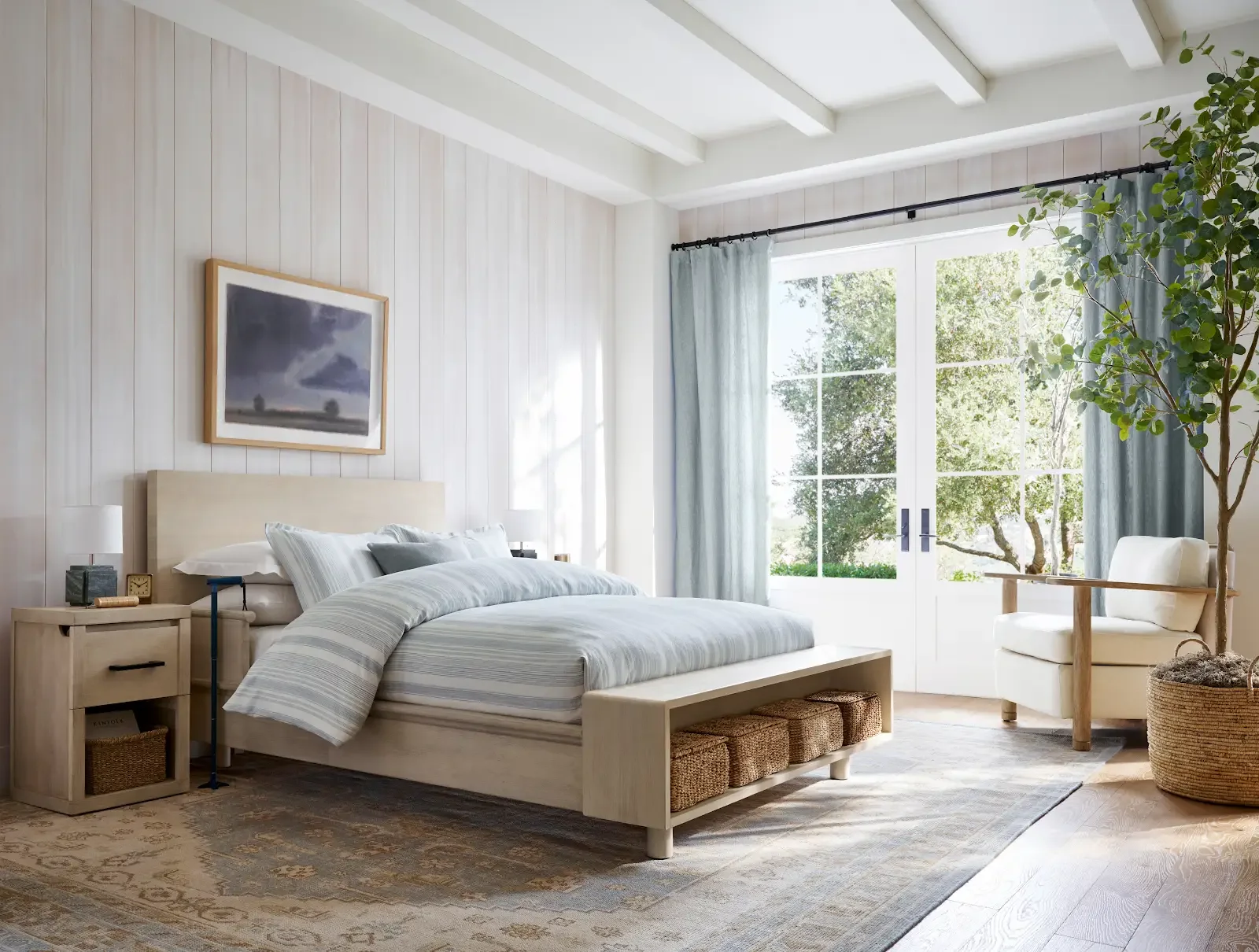 Michael Graves Design’s first Pottery Barn collection, with a timber bed, integrated bench, nightstand and armchair in a light-filled bedroom.