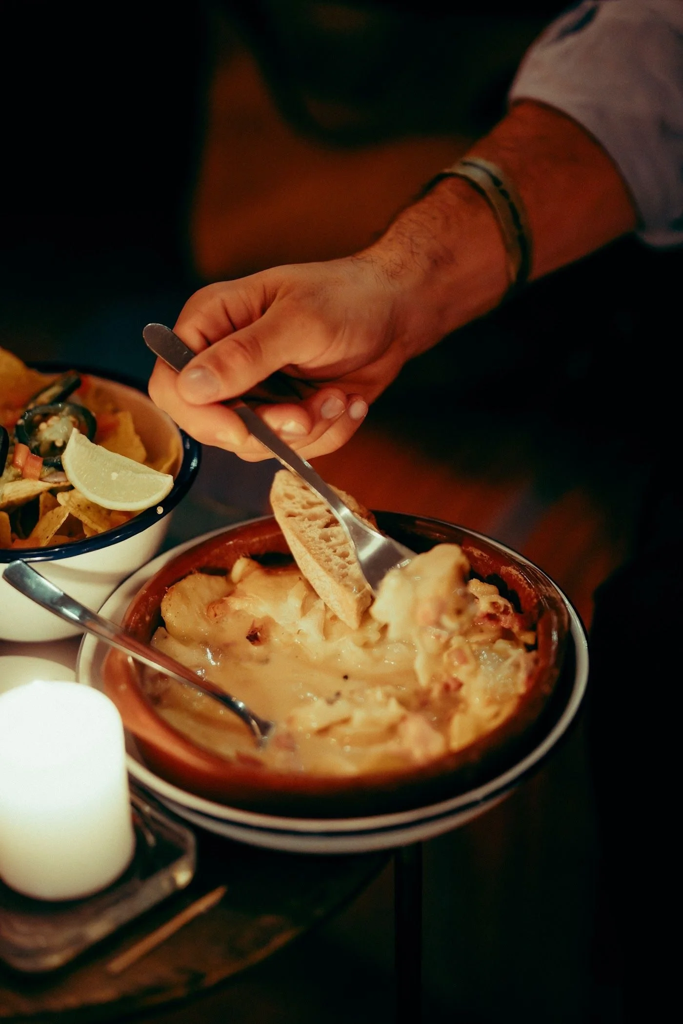 Baked cheese sharing dish served with bread, by candlelight