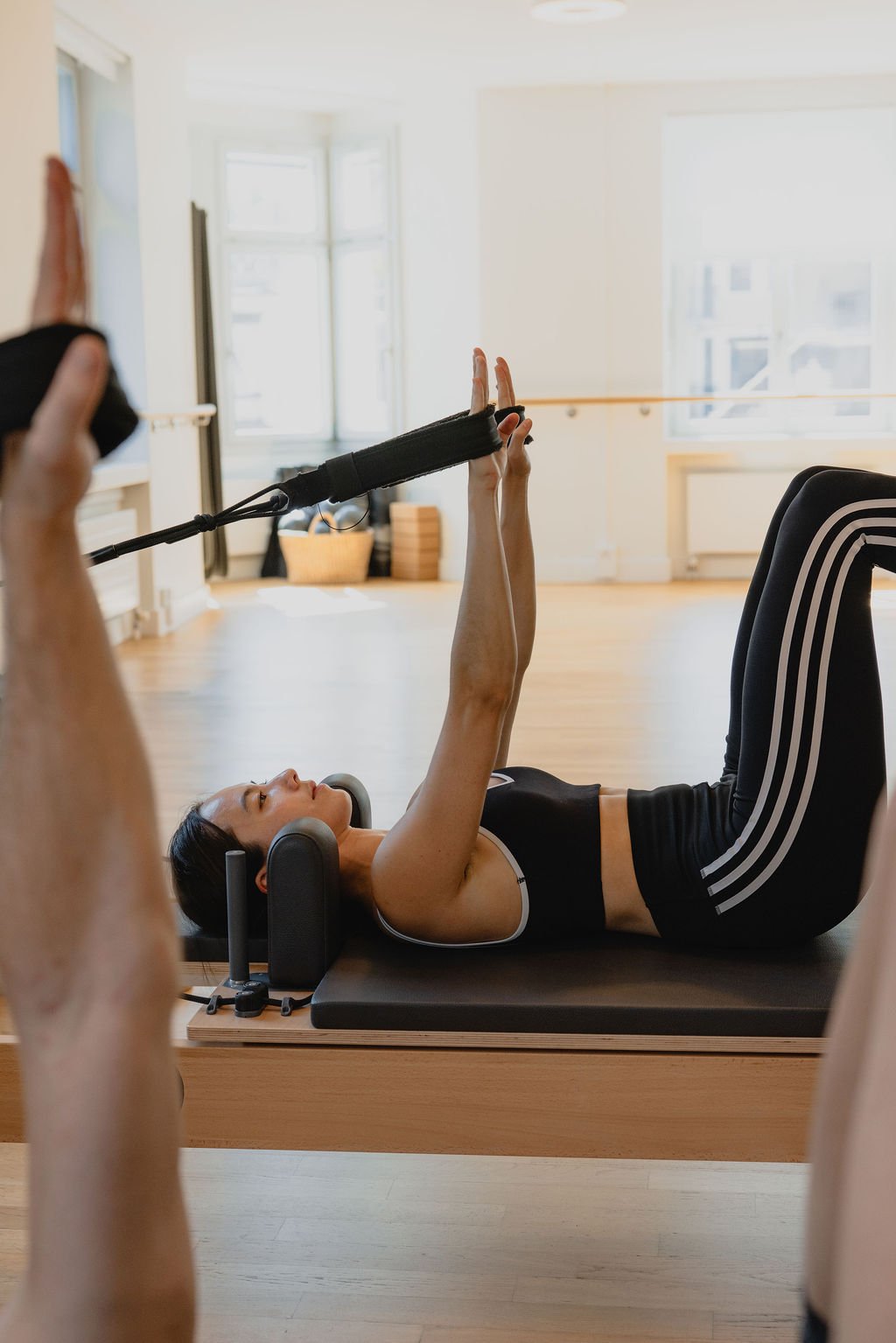 A client using Reformer straps during a group Pilates class