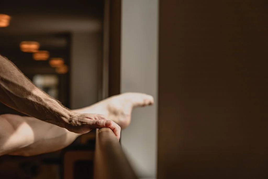 Hand and supported leg at the ballet barre