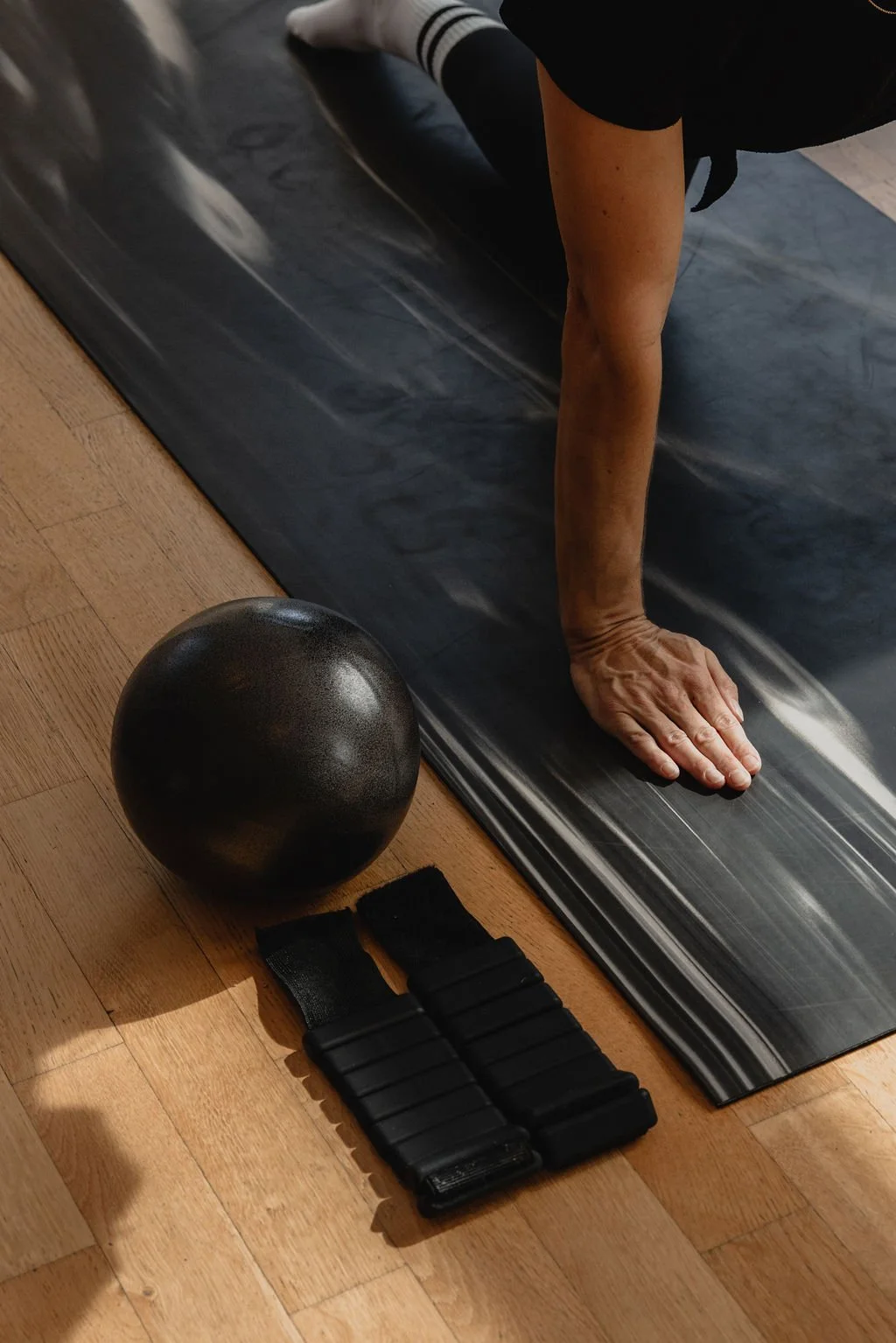 Close-up of Pilates Sculpt mat practice with a soft ball and wearable weights