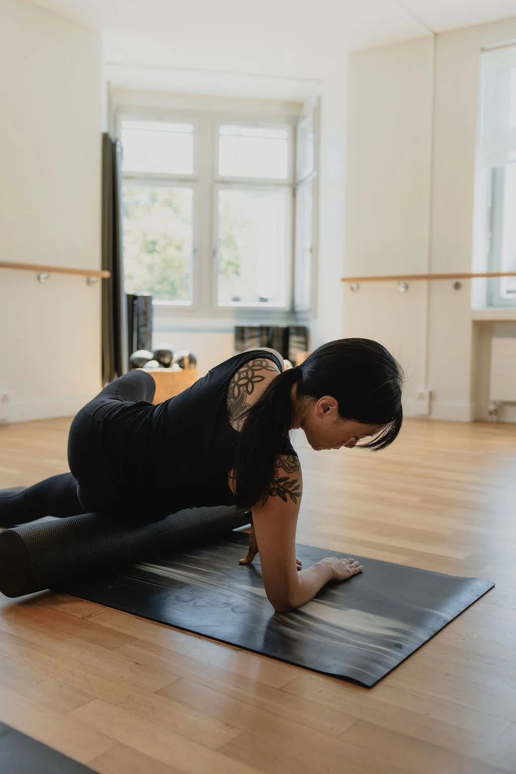 A client practicing Mat Pilates with a foam roller