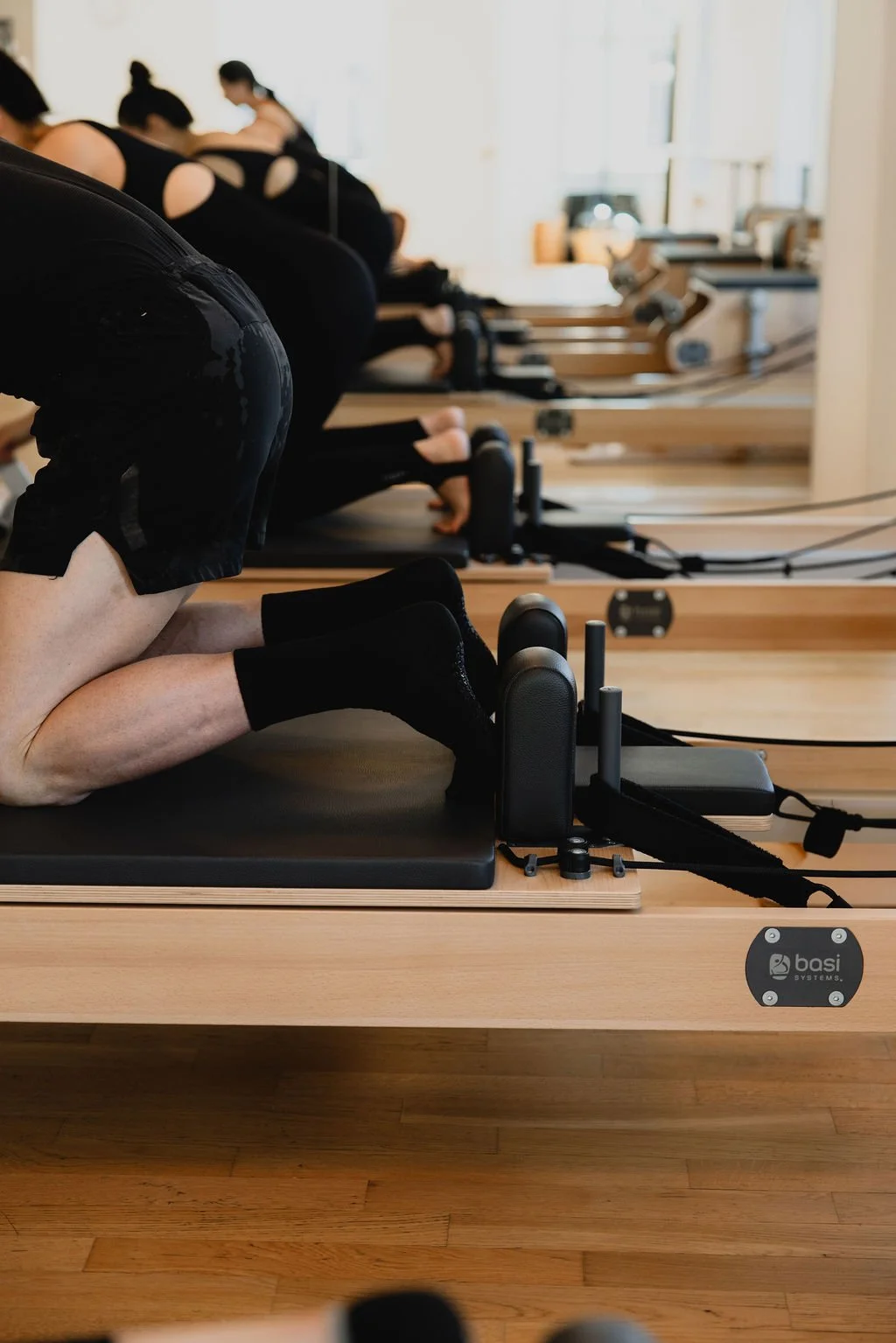Small-group kneeling Reformer practice at Studio Mōtus