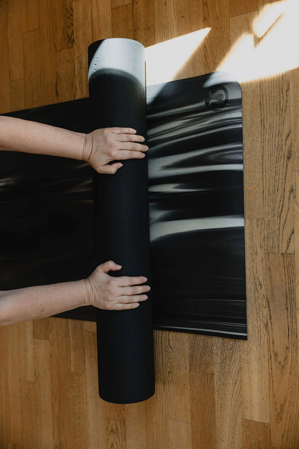 Hands working with a foam roller on the mat
