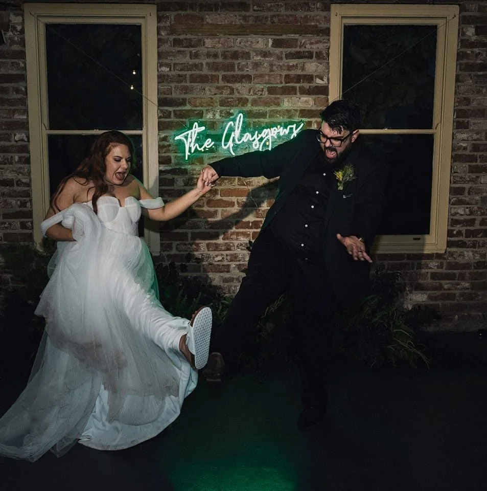 Dan Glasgow, Adelaide wedding photographer and videographer, dancing with his wife beneath their neon sign