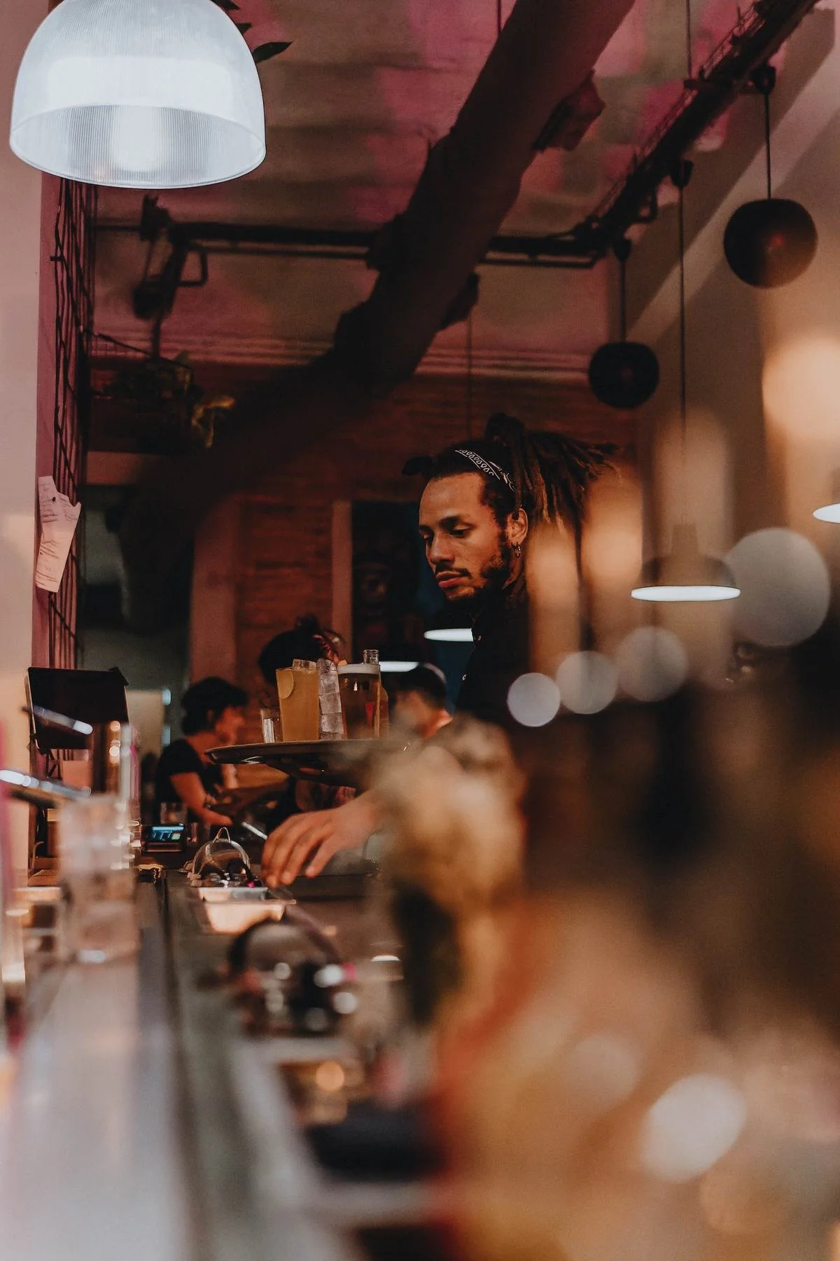La barra larga de noche, con un bartender trabajando.