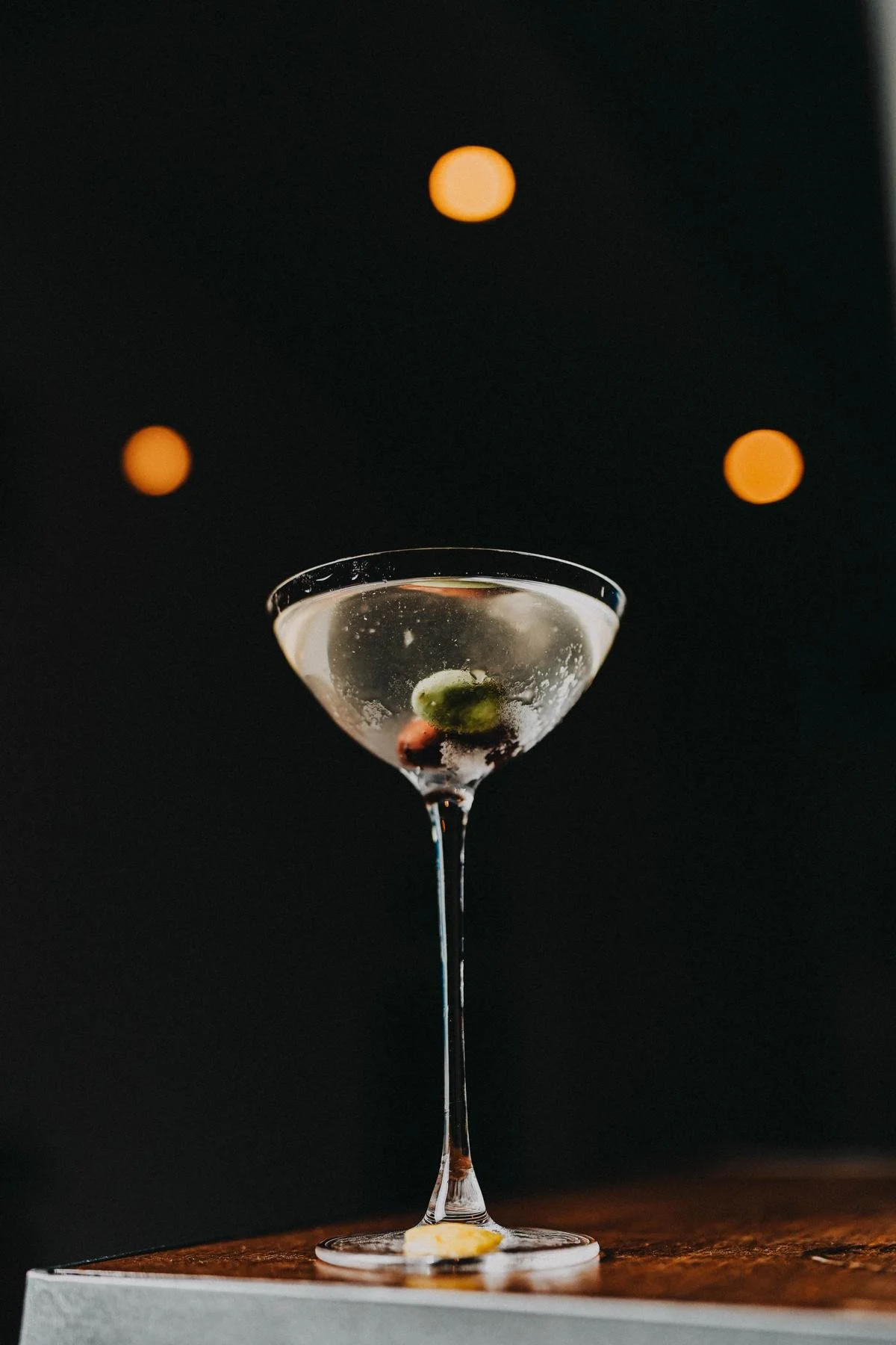 Un Martini en la barra, con luces cálidas detrás.