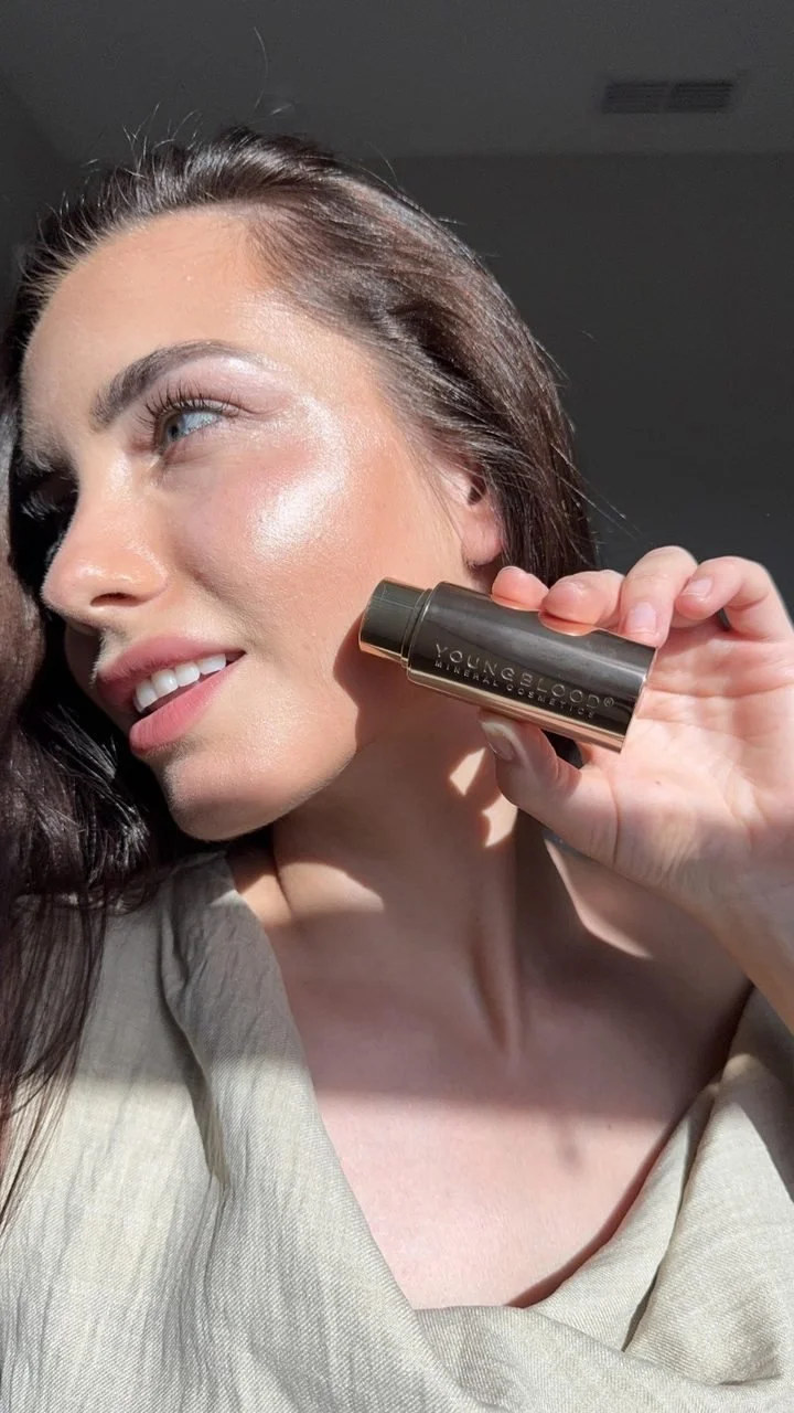 A creator in sunlight holding a Youngblood stick to her cheekbone