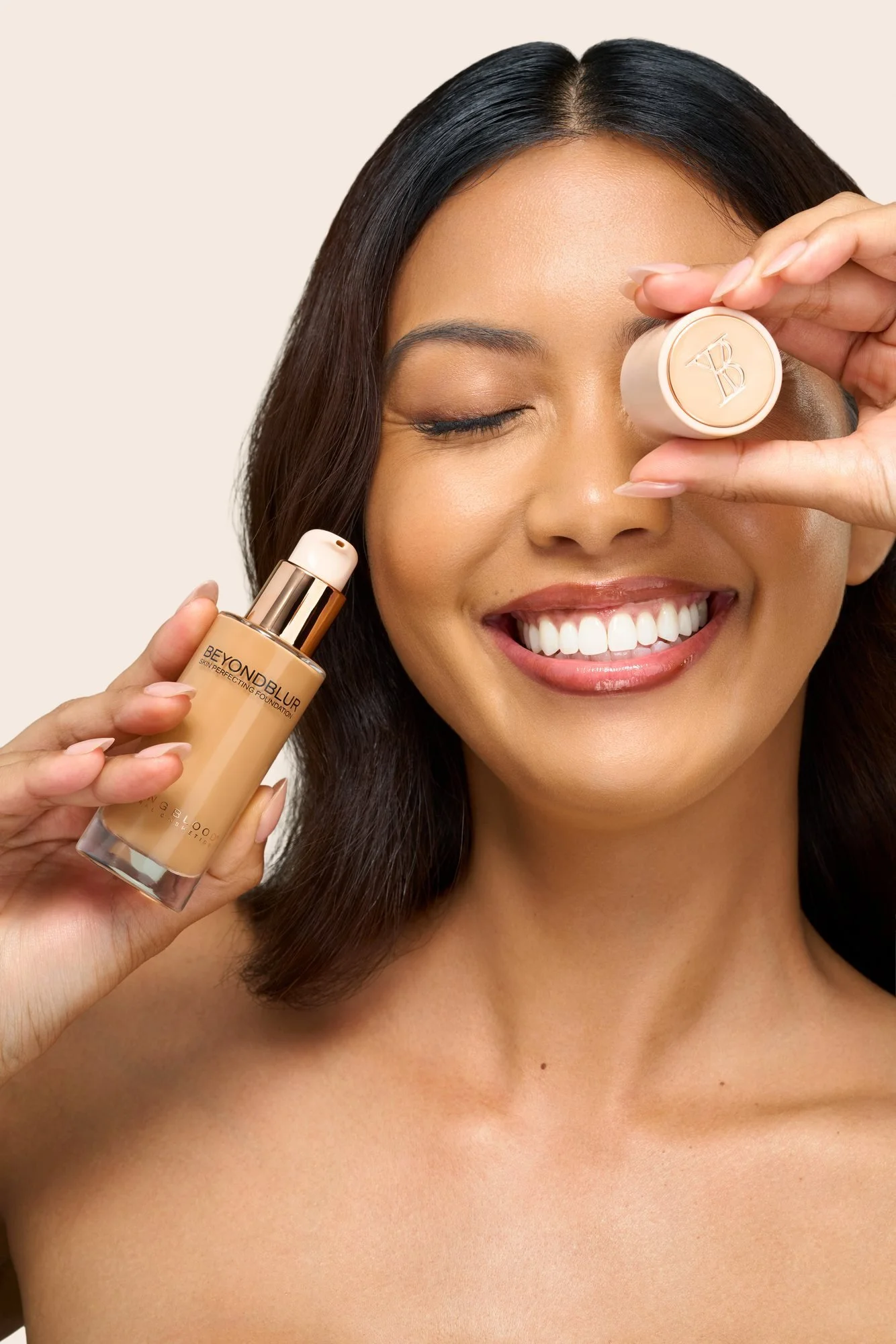 A smiling model holding a bottle of BeyondBlur Skin Perfecting Foundation and its cap