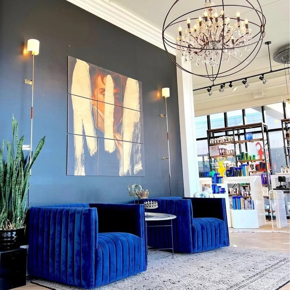 Blue velvet chairs under a chandelier in the Haus of Heir front lounge