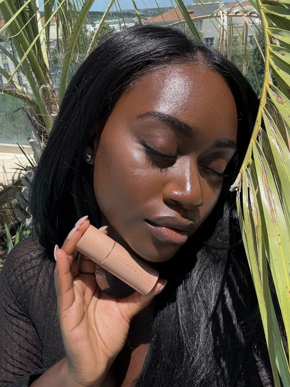 A creator in the sun holding a Youngblood stick to her cheek