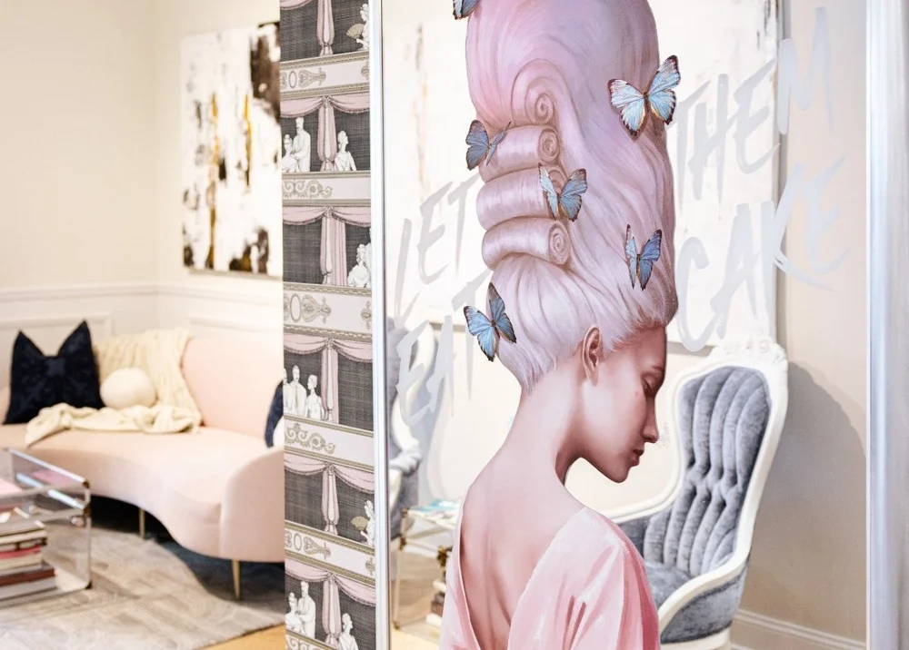 A pink portrait mural with butterflies beside a cream sofa