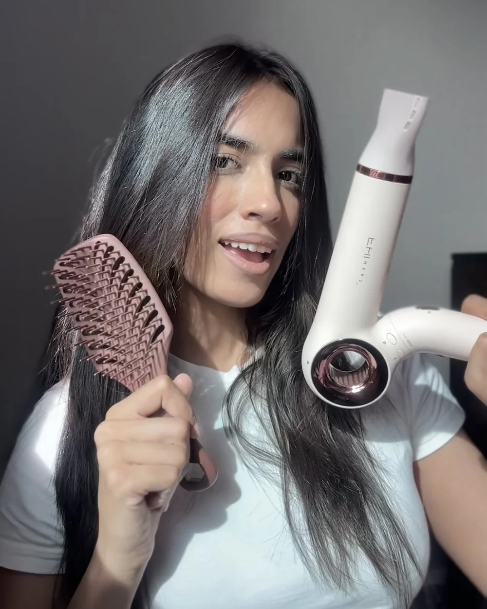 A creator holding a detangling brush and a hair dryer