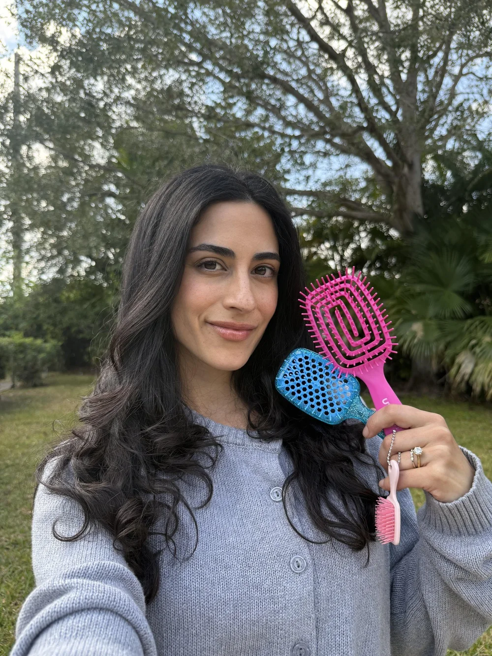 A creator holding three detangling brushes