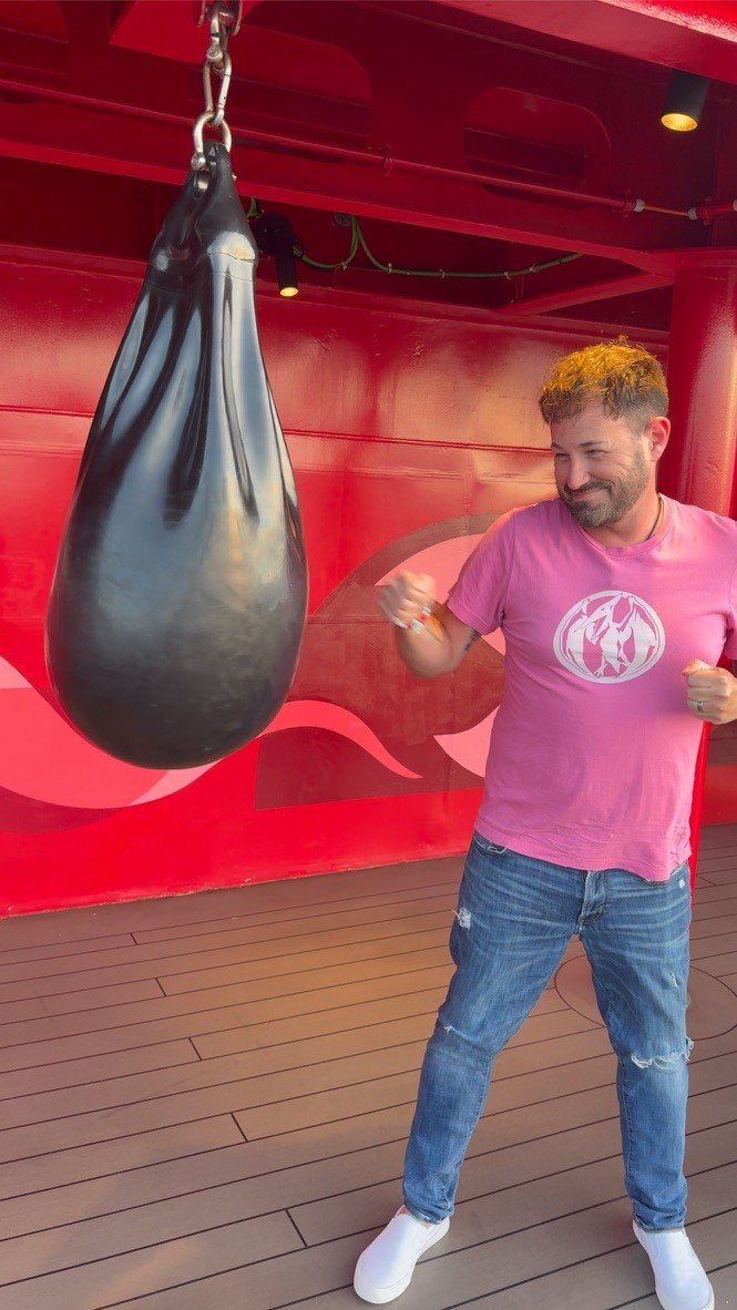 Sean Bryan having fun at a punching bag on a cruise ship sports deck