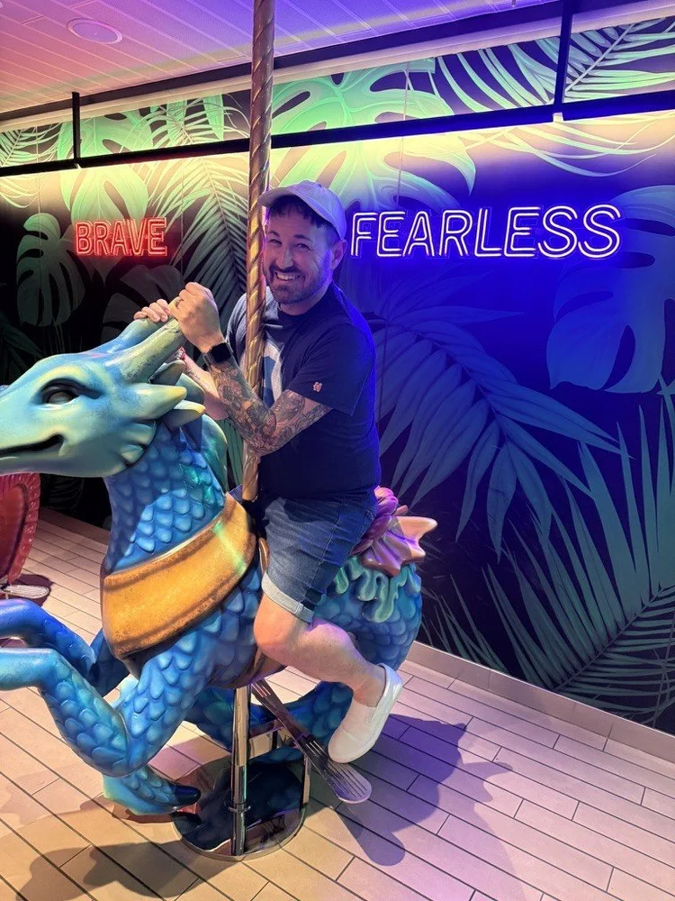 Sean Bryan riding a dragon carousel on a cruise ship