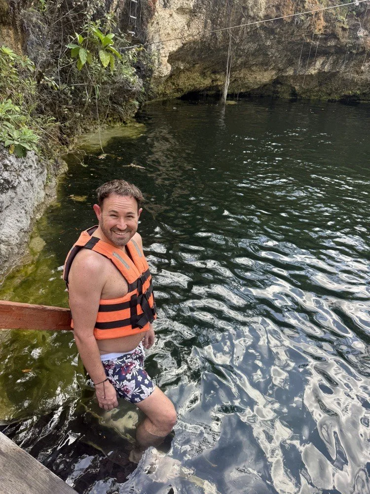 Sean Bryan in a life jacket stepping into a cenote in Mexico