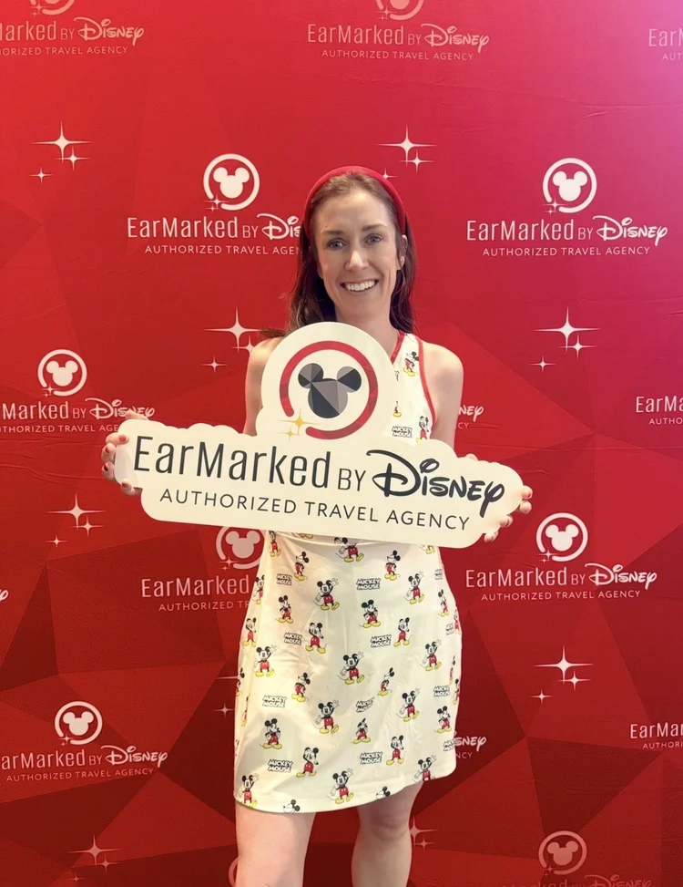 Danielle Casey with the EarMarked by Disney Authorized Travel Agency sign