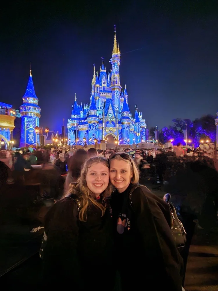 Kara Hull and her daughter in front of Cinderella Castle lit up at night at Magic Kingdom