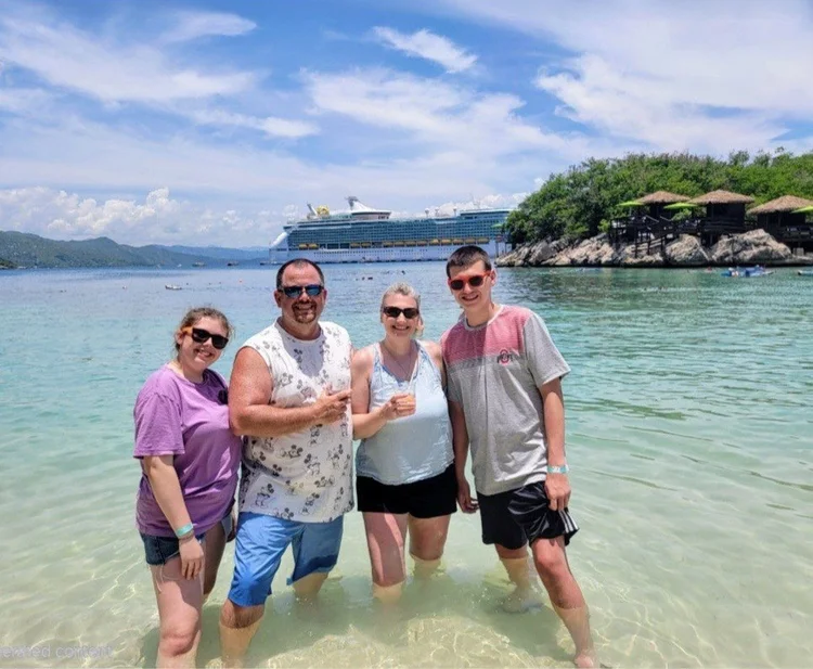 Kara Hull and her family in the water at Labadee with a Royal Caribbean ship behind them