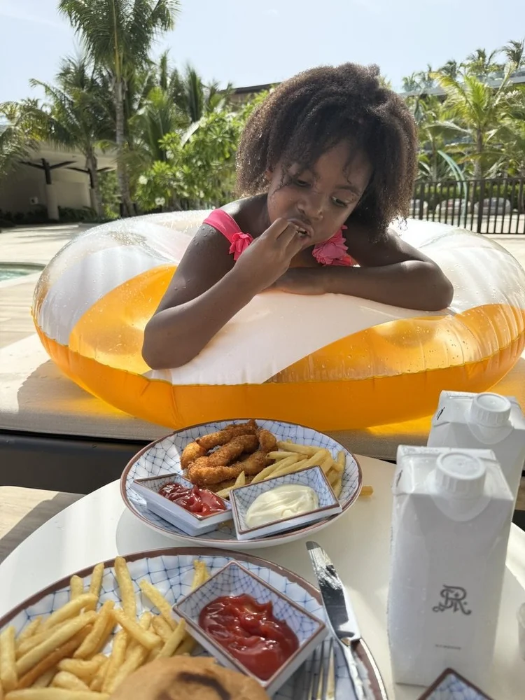 Piper Bryan taste testing chicken nuggets by the pool in Punta Cana