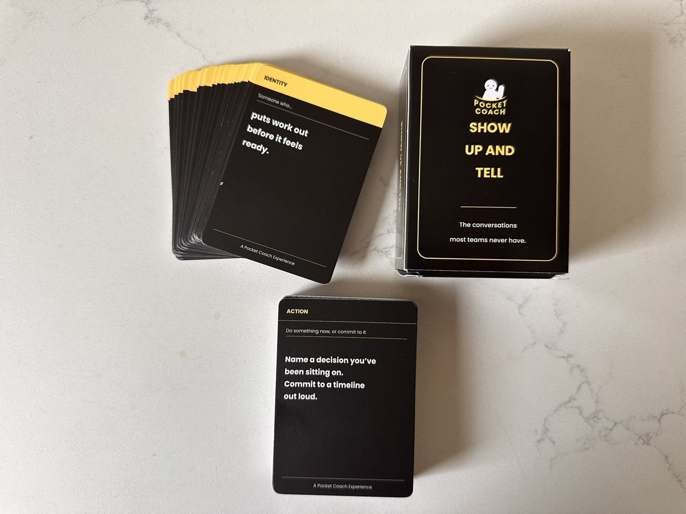 The Show Up And Tell box with an Identity card and an Action card on a marble table