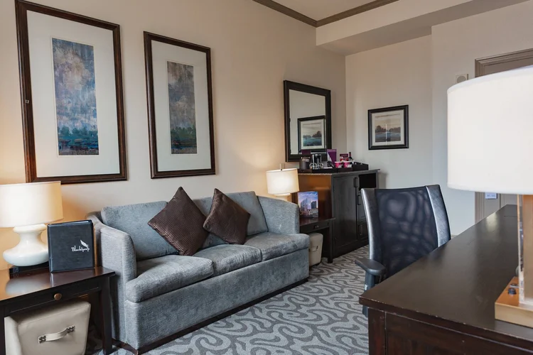 Guest room seating area with a sofa, framed art and a work desk