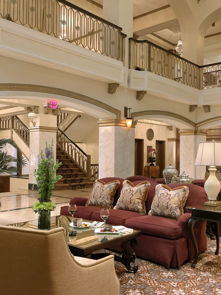 Lobby seating area with a red sofa, armchairs and a sweeping staircase