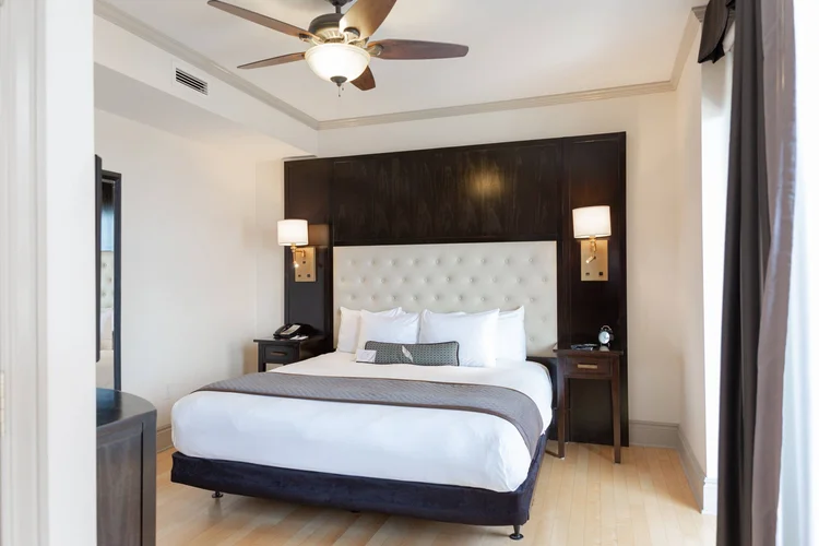 Suite king bedroom with a tufted headboard and ceiling fan