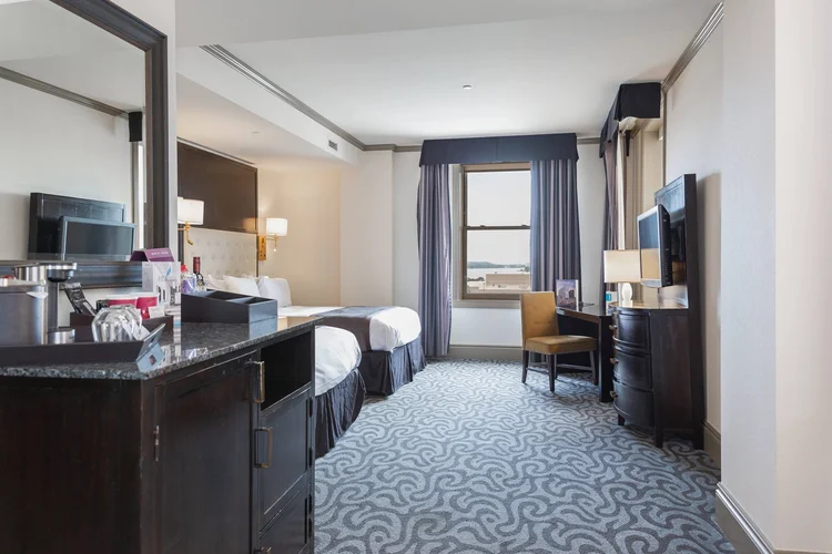 Queen-Queen guest room with two beds, a desk and a window