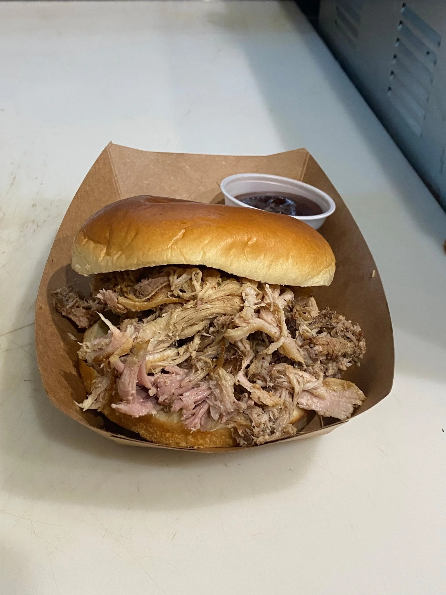 Pulled pork sandwich with barbecue sauce on the side