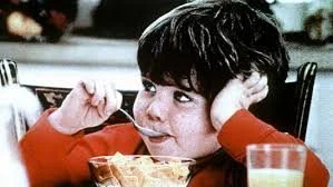Still from the Life cereal "Hey Mikey" television commercial: two boys push the bowl of an unfamiliar new cereal across the table to their younger brother to try first.