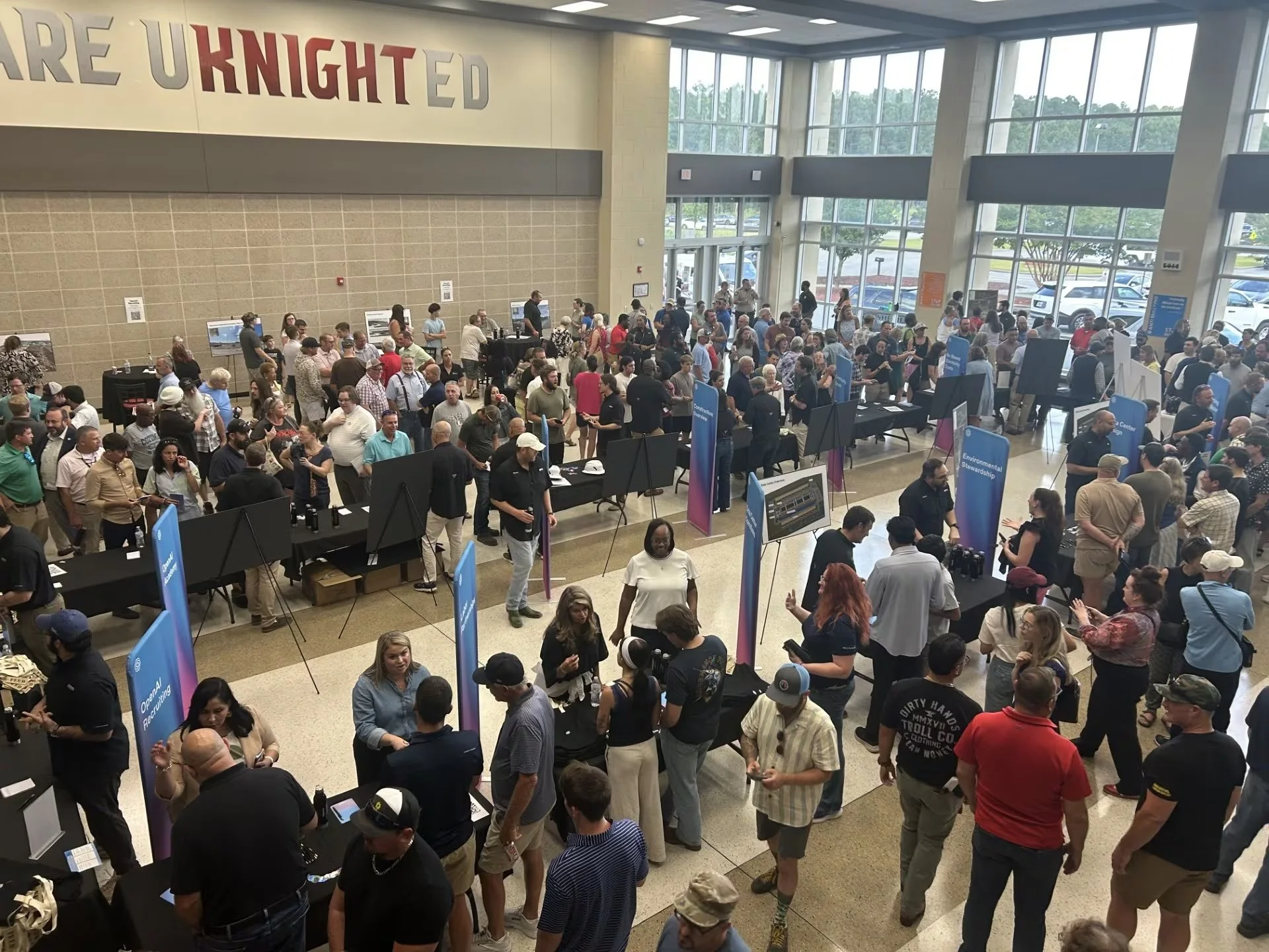 Hundreds of residents crowd the lobby of the Effingham County College and Career Academy, between OpenAI recruiting banners and display easels.