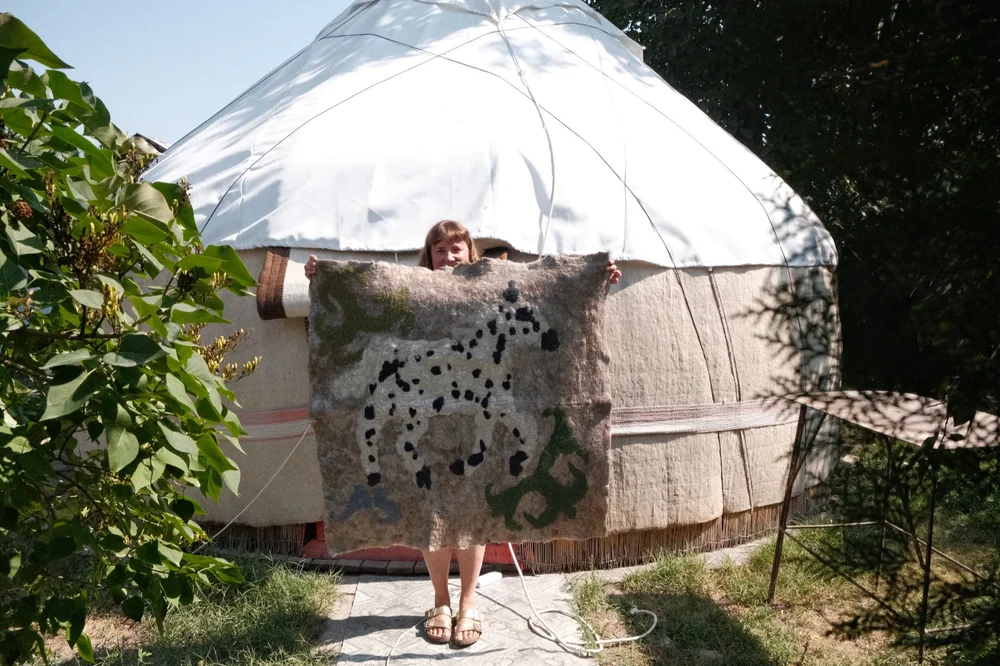 A felt spotted horse made in a Kyrgyz felt workshop, held up outside a yurt