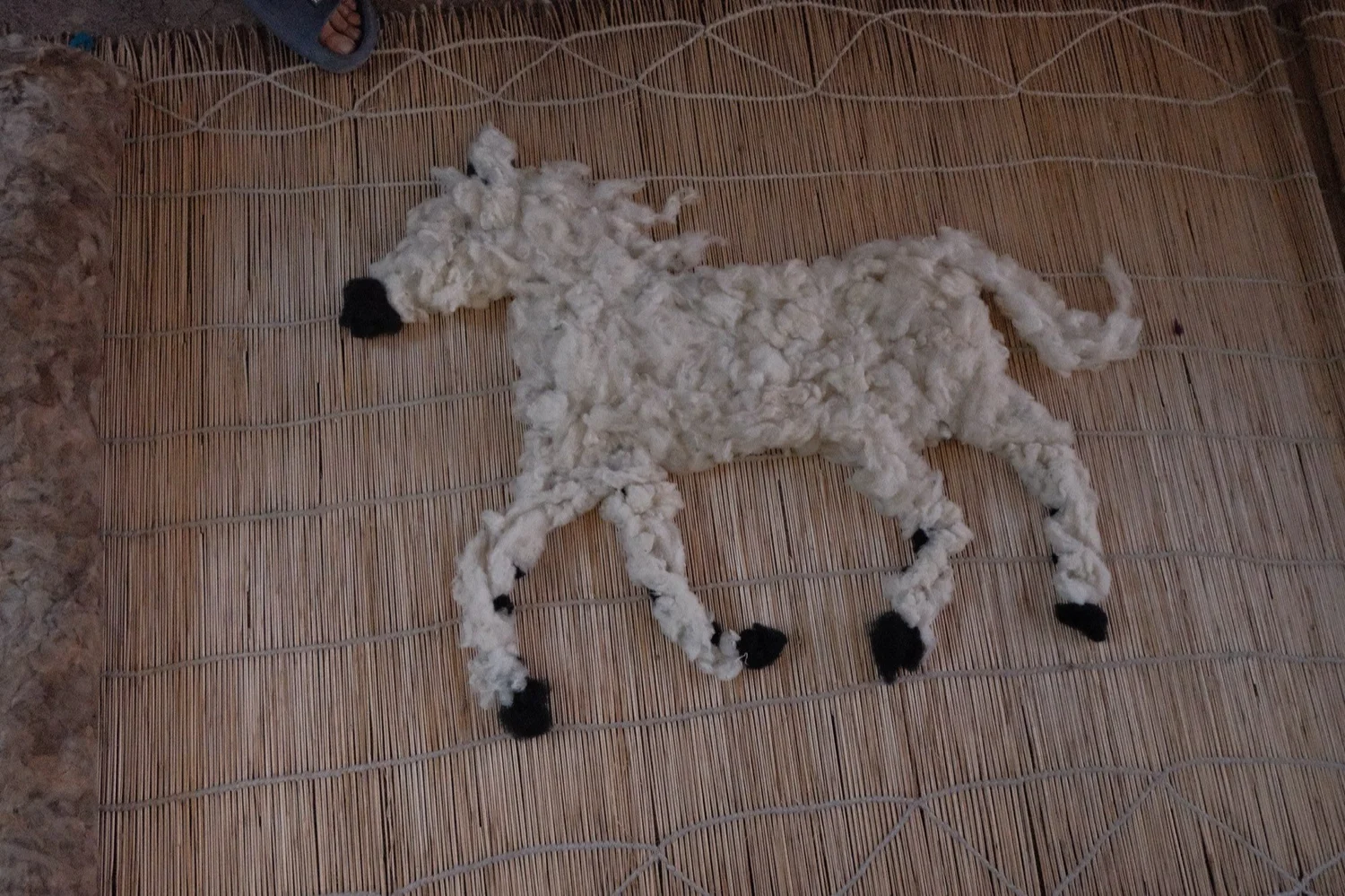 A felt horse design laid out in wool at the felt workshop