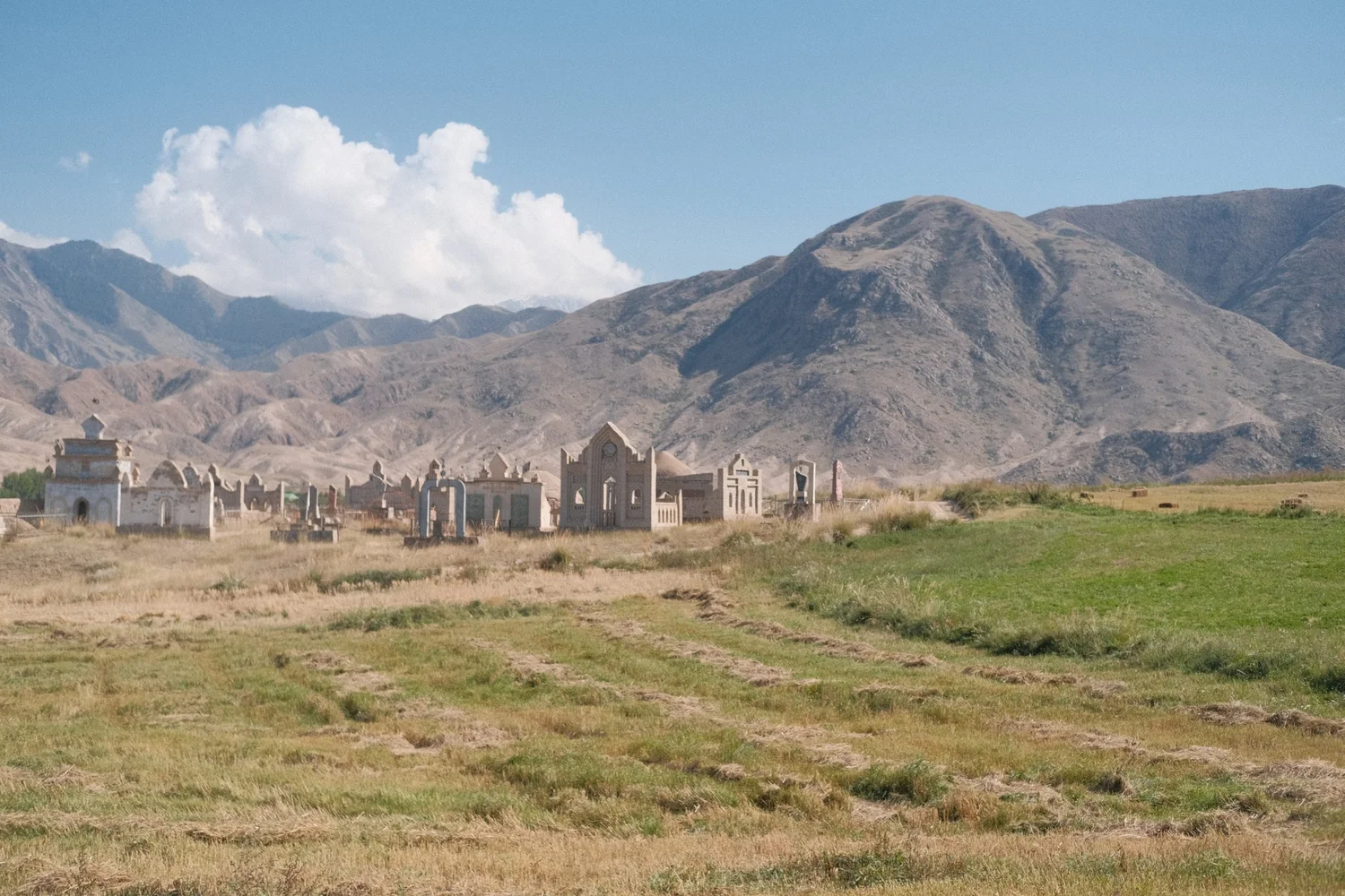 Traditional Kyrgyz mausoleums in a meadow beneath the mountains