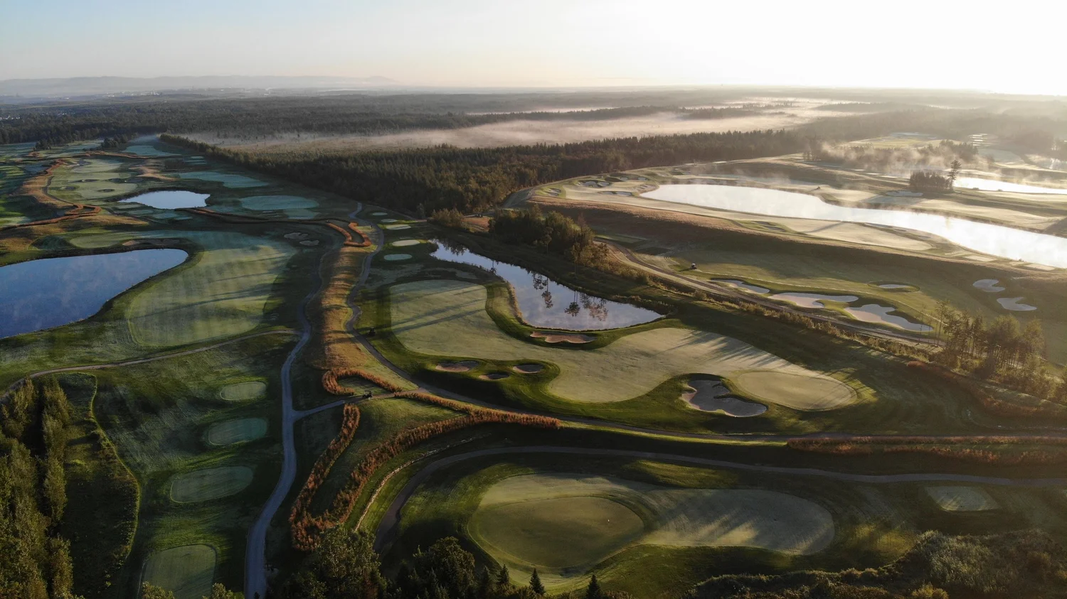 Vue aérienne du Golf La Tempête au lever du soleil avec brume matinale sur les fairways