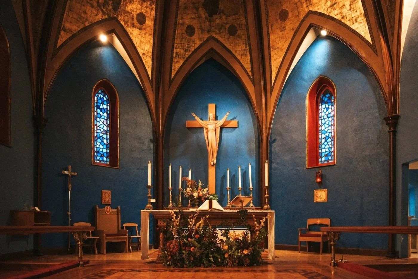 The empty sanctuary at St. John's: blue walls, a painted gold ceiling and stained glass behind the altar