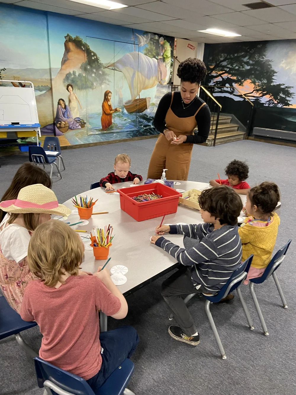 Chelsy DeHart leading a Sunday School craft table in the St. John's mural room